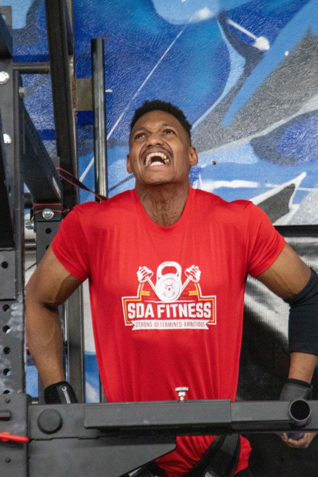 Coach Shai Ariola, USA Streetlifting champion, mid-set on a heavy weighted pull-up with a plate-loaded dip belt